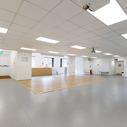 Spacious community hall with an open floor plan, projector, and flexible space for gatherings and classes.