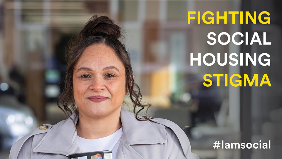 Headshot of Hayley looking at the camera smiling. Hayley has a bun hairstyle and grey jacket on. On the right of the image is text that reads: FIGHTING SOCIAL HOUSING STIGMA #iamsocial
